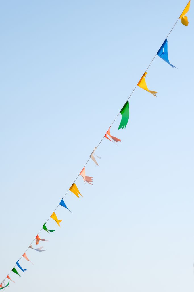 Vibrant bunting flags hanging against a clear blue sky, perfect for celebration themes.